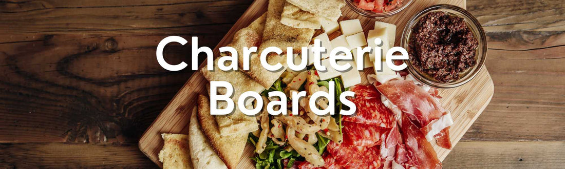 A charcuterie board on a wooden table featuring cured meats, cheeses, crackers, olives, and spreads, with "Charcuterie Boards" text overlay.